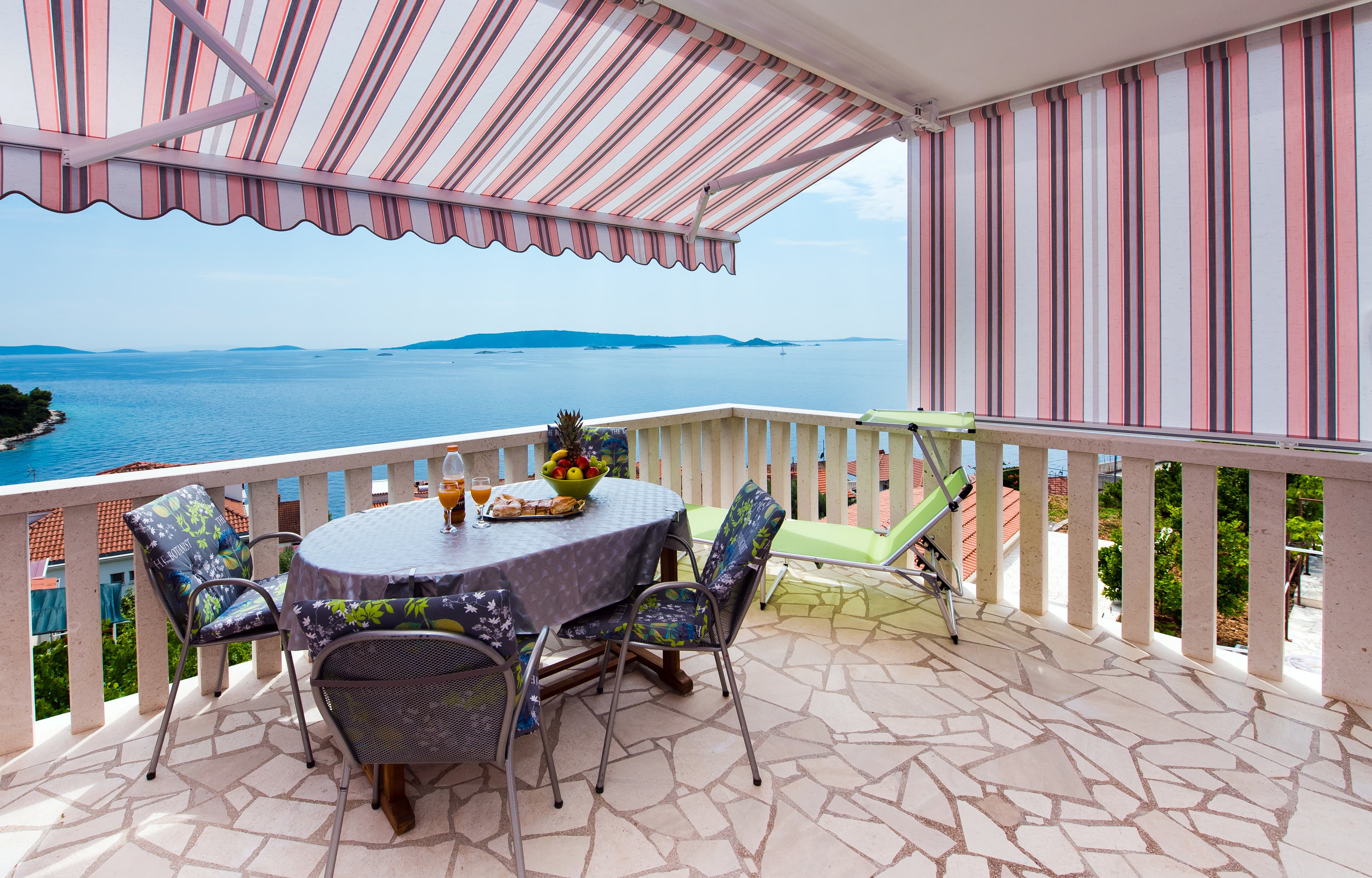 Terrace dining under striped awning overlooking the sea